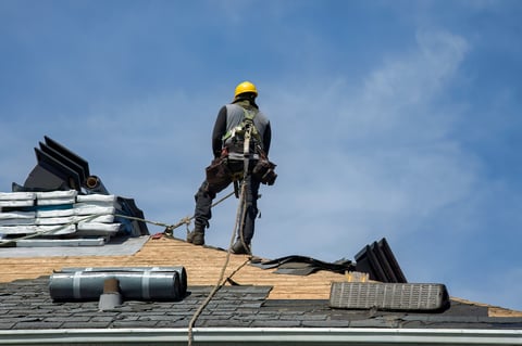 Construction worker installing new roof with safety helmet